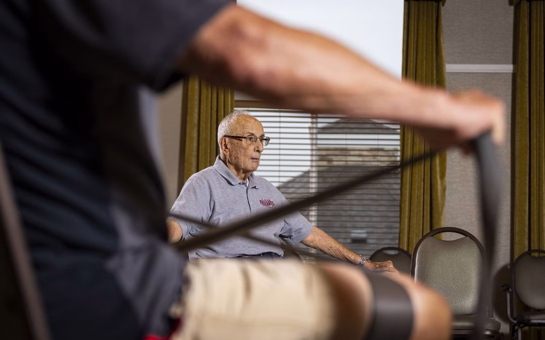 A resident strengthens his arms with resistance bands at Willow Brook Run, where regular wellness programming supports active senior living in Delaware, Ohio.